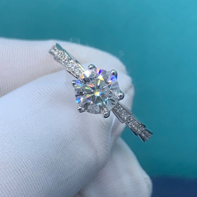 Silver ring with a large diamond held by white gloves against a teal background