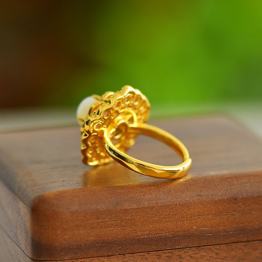 Gold ring with intricate design on a wooden surface with a blurred green background
