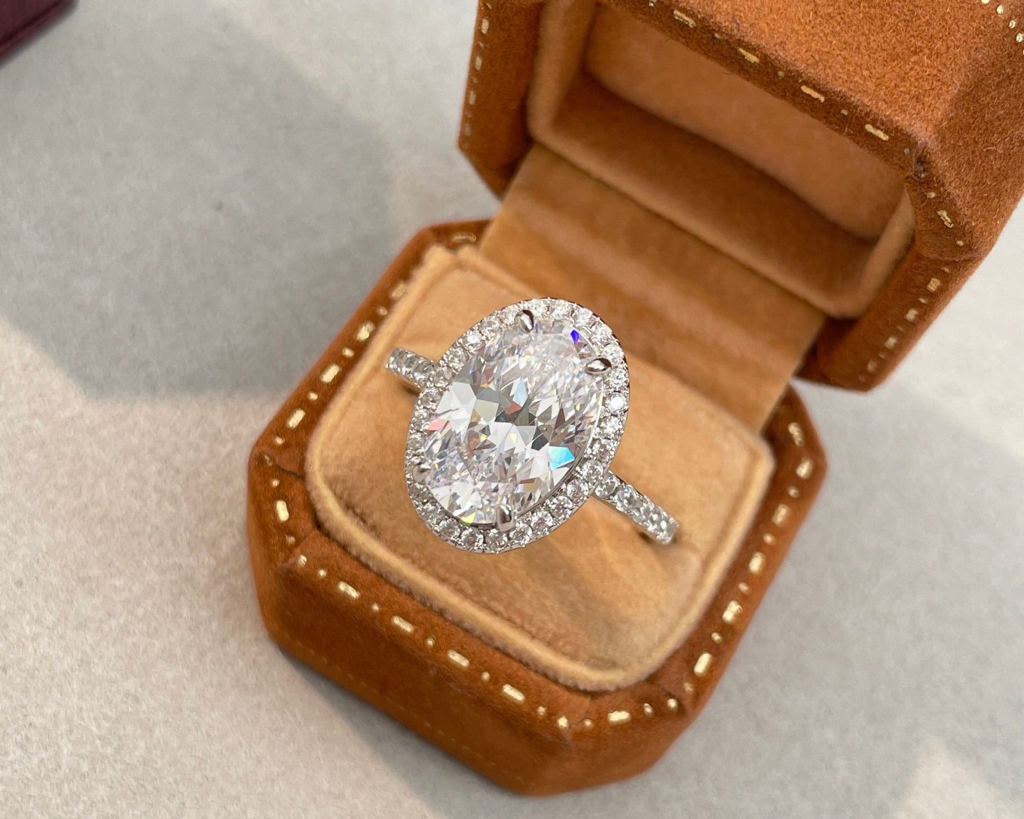 Diamond ring in an open brown velvet jewelry box on a light gray background
