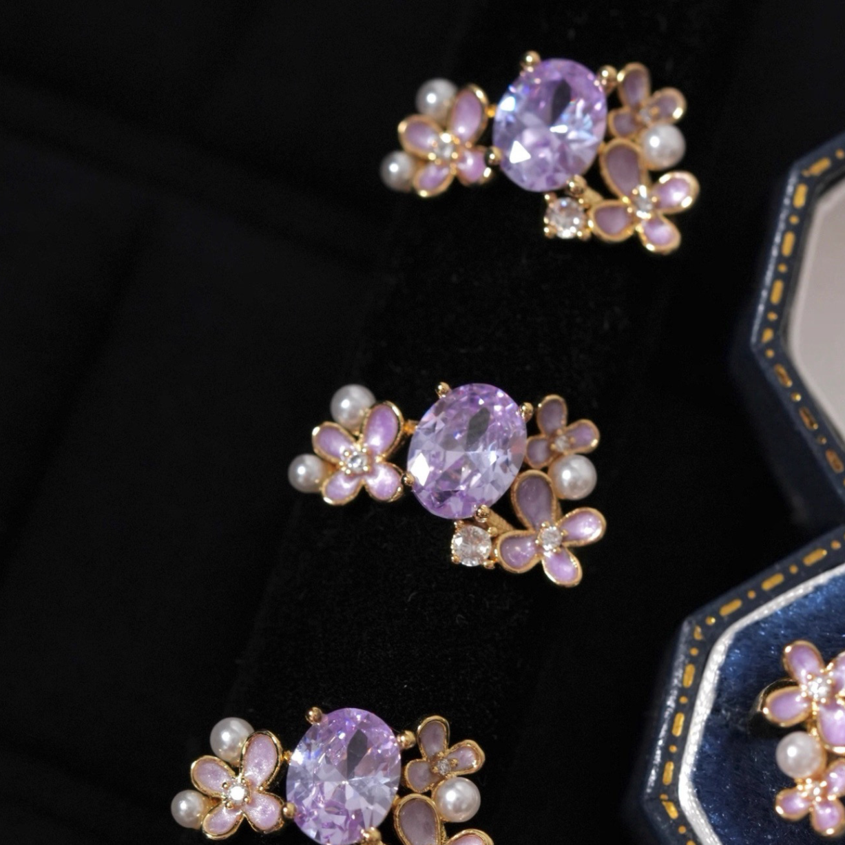 Pair of earrings with purple gemstones and pearl-like elements on a dark background