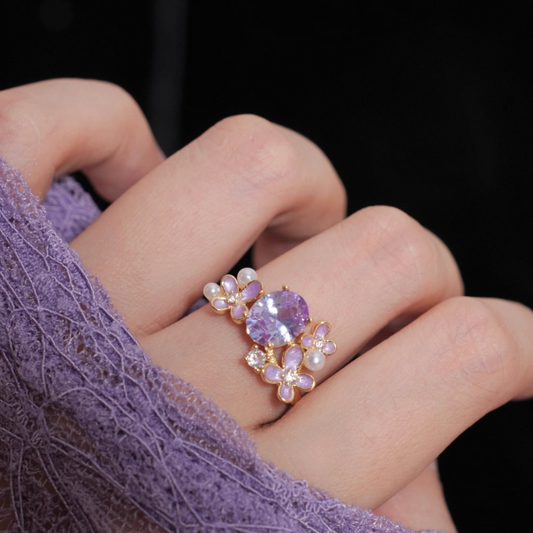 Close-up of a hand wearing a decorative ring with a purple gemstone.