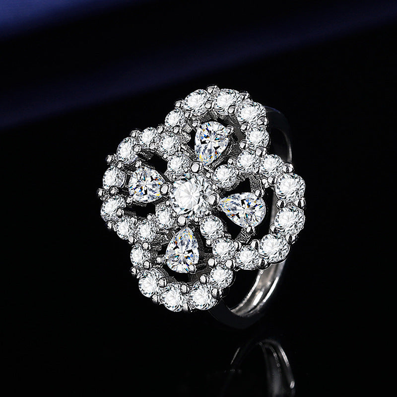 Silver ring with diamond flower design on a black background