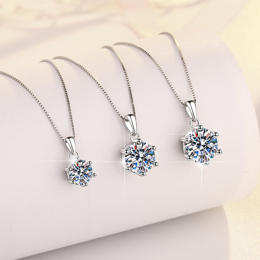 Three silver pendants with clear gemstones on a soft white background