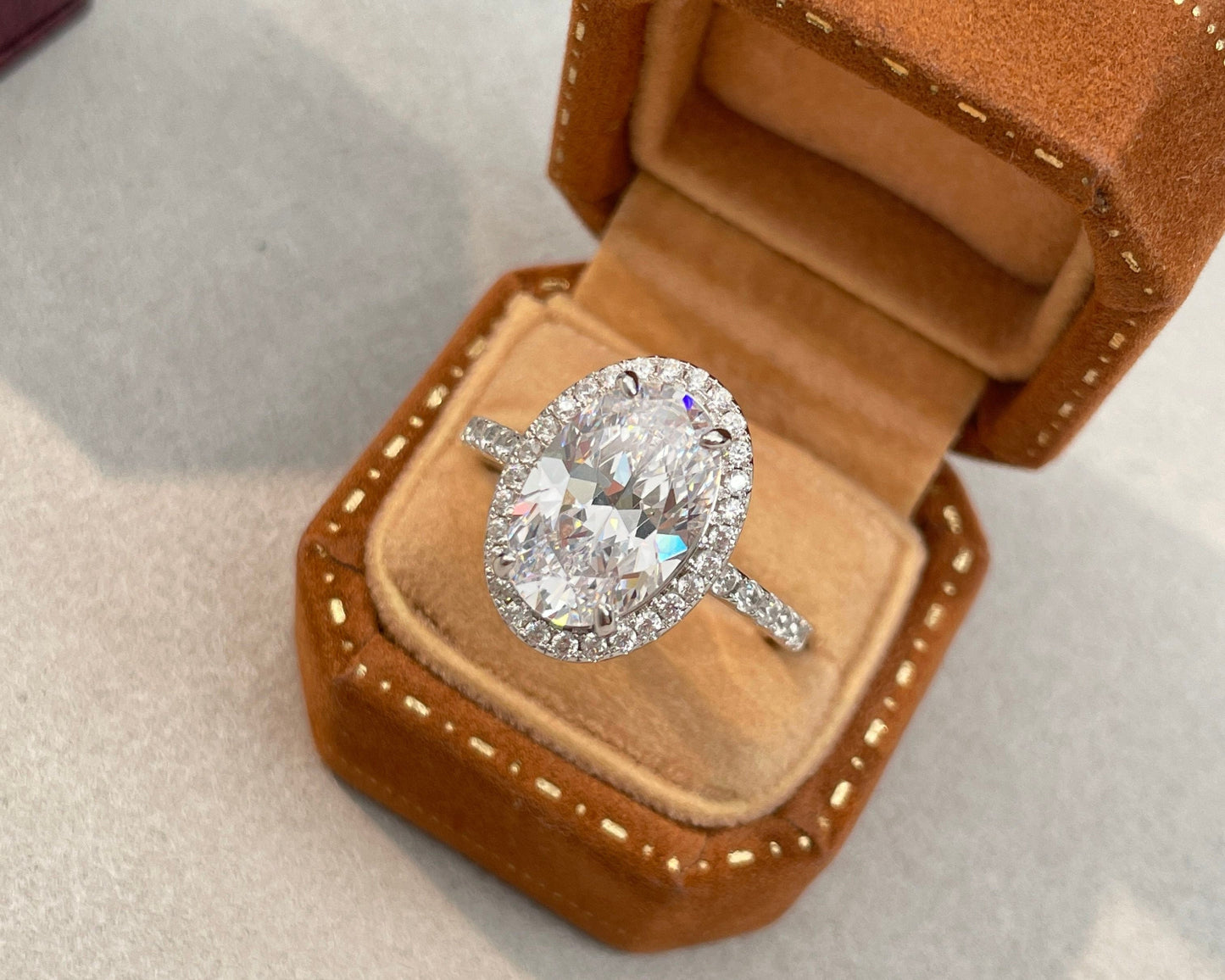 Diamond ring in an open brown velvet jewelry box on a light gray background
